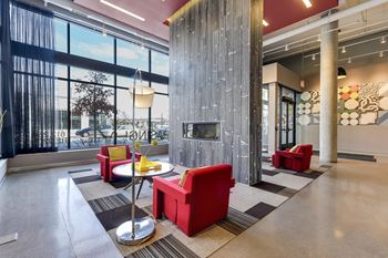 Apartment lobby with central fireplace that reaches ceiling, arms chairs on either side